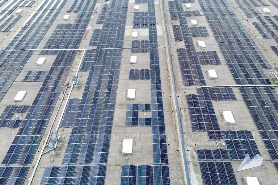 Großflächige Photovoltaikanlage (Solarmodule) auf dem Flachdach eines großen Logistikgebäudes