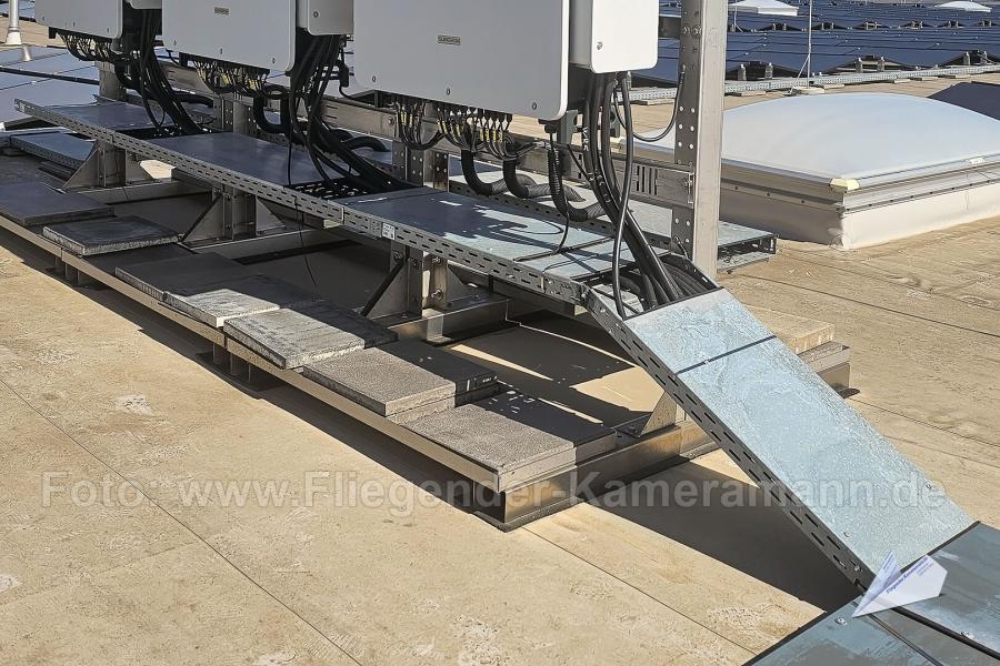 Unterkonstruktion für PV-Anlage, bestehend aus Wechselrichtern, ballastierten Montagesystem und galvanisierten Kabeltrassen (Kabelkanälen).