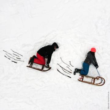 Foto mit Drohne: Luftaufnahme Kinder mit Schlitten im Schnee