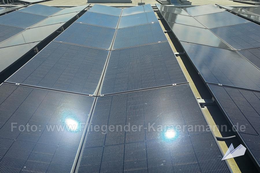 Luftaufnahme von Solarmodulen (Photovoltaikanlage) in Ost-West-Aufständerung auf einem Flachdach.